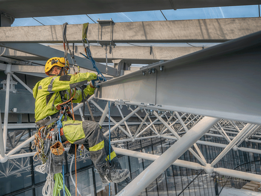 Rope access technician working on structural steelwork during inspection and testing