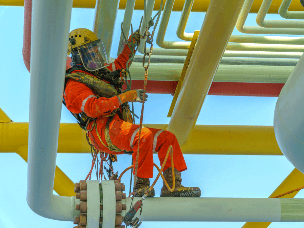 Rope access technician carrying out maintenance on dockside steelwork and pipework